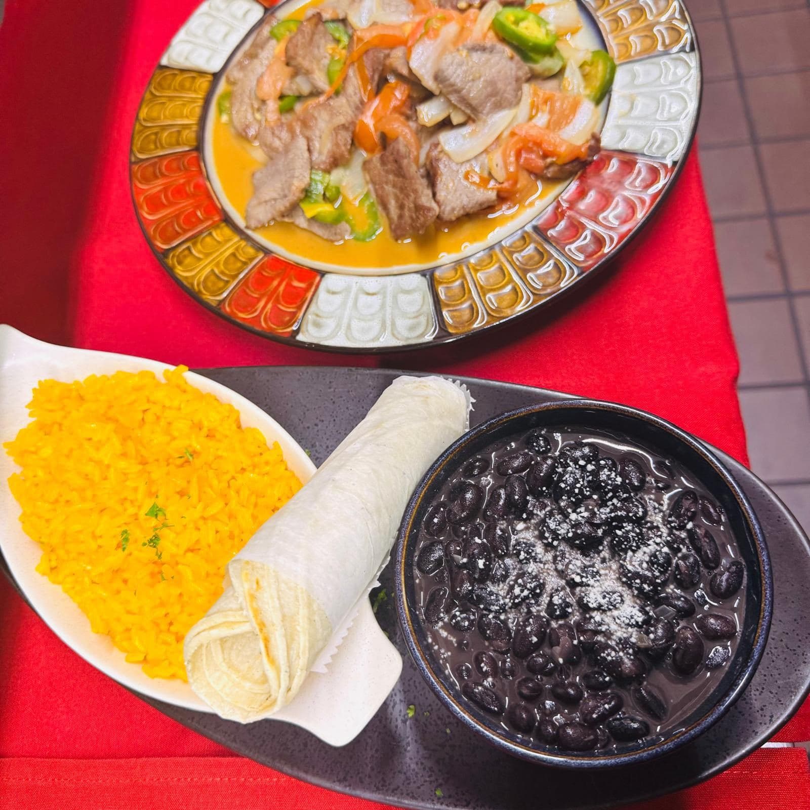Steak and onions with yellow rice, beans and tortilla