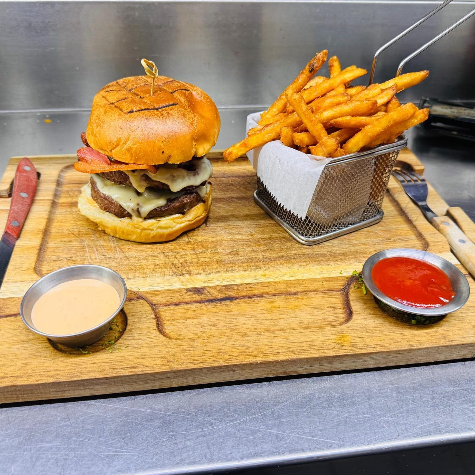 Double bacon cheeseburger with fries on a wooden board